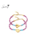 Roze gekleurde armbanden met een goudkleurige smily en een hart