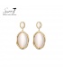 Beige oorbellen met een goudkleurige rand en een cat eye steen